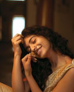 a woman smiles as she holds her hair up to her face