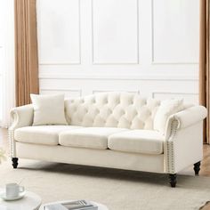 a white couch sitting on top of a wooden floor next to a table and chair