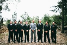 a group of men standing next to each other in front of trees and dirt ground