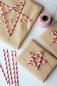 two wrapped presents with red and white striped straws on them, next to some candy canes