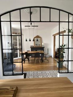 an arched glass door leads to a dining room and kitchen area with wooden table, chairs, and mirror