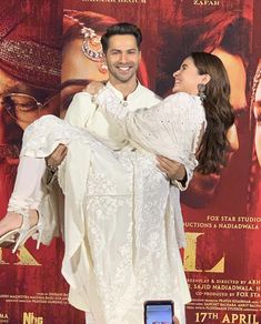 a man holding a woman in front of a movie poster