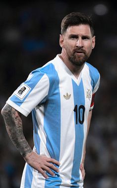 a man with tattoos on his arms and chest wearing a blue and white striped shirt