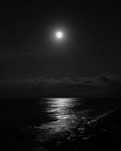 the moon is shining over the ocean at night