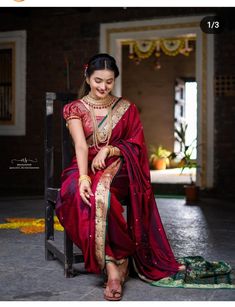 a woman in a red sari sits on a chair and smiles at the camera