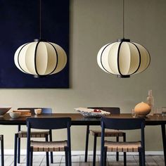 a dining room table with four chairs and two lamps hanging from the ceiling above it