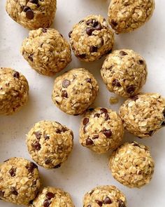 several balls of oatmeal and chocolate chip cookies on a white surface with one cookie in the middle