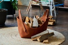 a basket filled with wood sitting on top of a rug