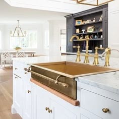 a kitchen with white cabinets and gold faucets