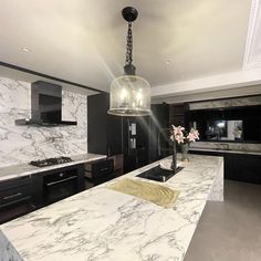 a large kitchen with marble counter tops and black cabinets, along with an island in the middle