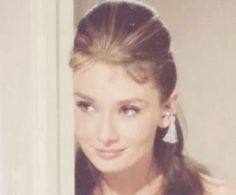 a young woman with long hair and earrings on her head is looking at the camera