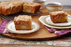 two pieces of cake sitting on top of plates next to coffee cups and saucers