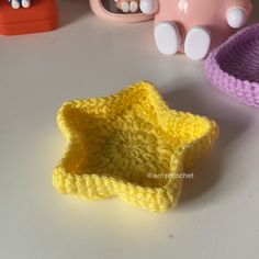 two crocheted dishes sit next to each other on a table with toys in the background