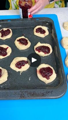 doughnuts are being made on a cookie sheet with jam in the middle and someone holding a bottle of ketchup