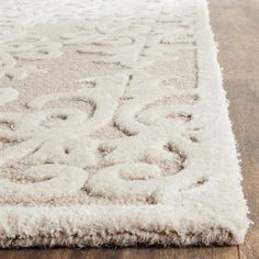 a white rug with an ornate design on the top and bottom, sitting on a wooden floor