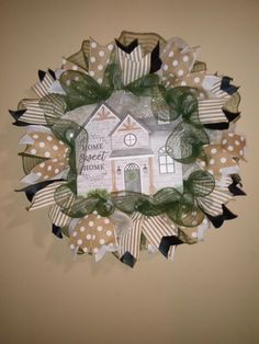 a wreath made out of paper and ribbon with a house on it's front