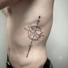 a man's chest with a compass tattoo on the side and an arrow in the middle