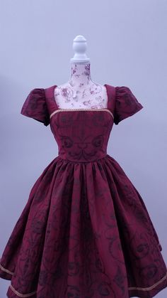 This rich in burgundy color is designed as a one-of-a-kind dress by PMdesigns by Pamela Marie. It has a gorgeous embroidery pattern throughout, and a gold trim around the hem of a full skirt with hidden pockets, and matching trim on the front bodice. The back is cut in a V, and has a zipper up the back. Suggested measurements: 34" Bust x 26" Waist x Hips Free Fitted Red Dress With Historical Design, Red Formal Dress With Historical Design, Elegant Burgundy Dress For Costume Party, Elegant Full Skirt Dress For Costume Party, Burgundy Evening Dress, Rich Burgundy, Full Skirts, Burgundy Color, Embroidery Pattern