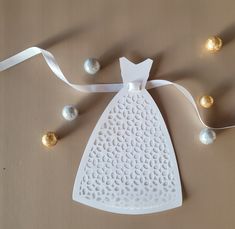 an ornament shaped like a dress hanging from a ribbon