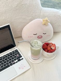 a laptop computer sitting on top of a bed next to a bowl of strawberries