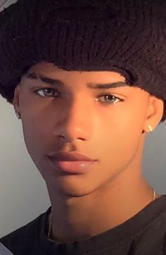 a close up of a person wearing a hat and looking at the camera with a serious look on his face