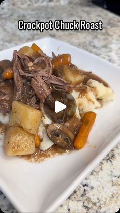 a white plate topped with meat and potatoes on top of a marble countertop covered in gravy