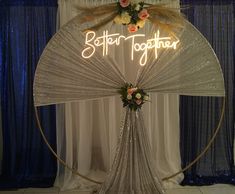 a lighted sign that says better together with flowers in the center and an umbrella behind it