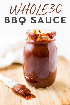 a jar filled with bbq sauce sitting on top of a wooden cutting board next to a knife