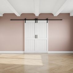 an empty room with pink walls and two white closet doors on the wall, in front of a parquet floor