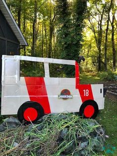 a fire truck made out of cardboard sitting in the grass next to some rocks and trees