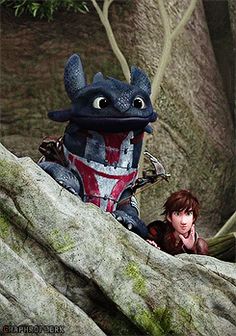 a woman standing next to a stuffed animal on top of a rocky hillside with trees in the background