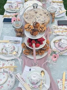 a table topped with plates and cups filled with desserts on top of each other