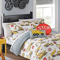 a bed with construction vehicles on it and a stop sign in front of the bed