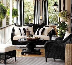 a living room with black and white furniture on the front porch, potted plants