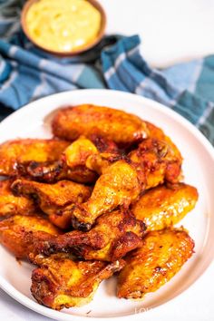 chicken wings on a white plate with mustard sauce in the backgroud and blue napkin