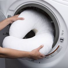 a person holding a roll of toilet paper in front of a washer machine with the door open