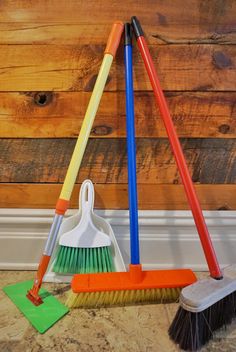 three brooms and two brushes are on the floor