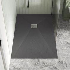 a bathroom with grey tile flooring and a shower head mounted to the side of the wall