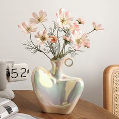 a vase filled with pink flowers on top of a wooden table