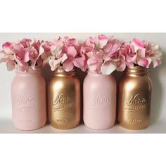 three pink and gold mason jars with flowers in them