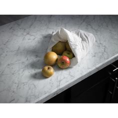 some apples and an apple in a bag on a marble counter top with black appliances