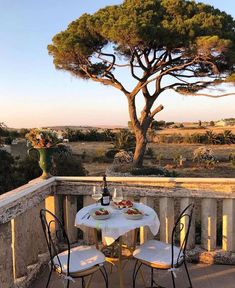 a table and chairs on a balcony with a bottle of wine in the foreground