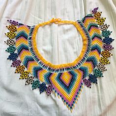 a multicolored crocheted necklace is displayed on a white cloth