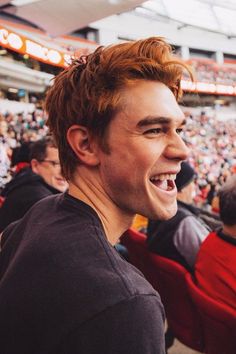 a man with red hair is laughing in the stands