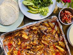 an assortment of food on a table including tortillas, salad and pita bread