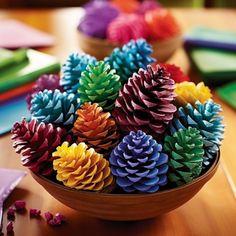 colorful pine cones are in a bowl on a table with colored crayons nearby