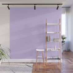 an empty room with a purple wall and wooden flooring in the corner, there is a ladder leaning against the wall