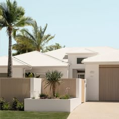 a white house with palm trees in the front yard and fenced area around it