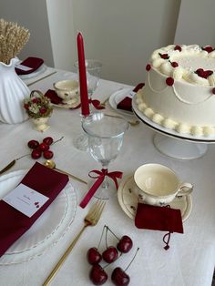 a table topped with two cakes covered in white frosting and cherries next to red napkins