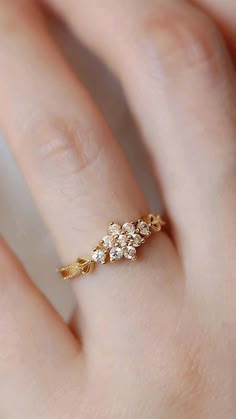 a woman's hand with a gold ring on it and three small white stones